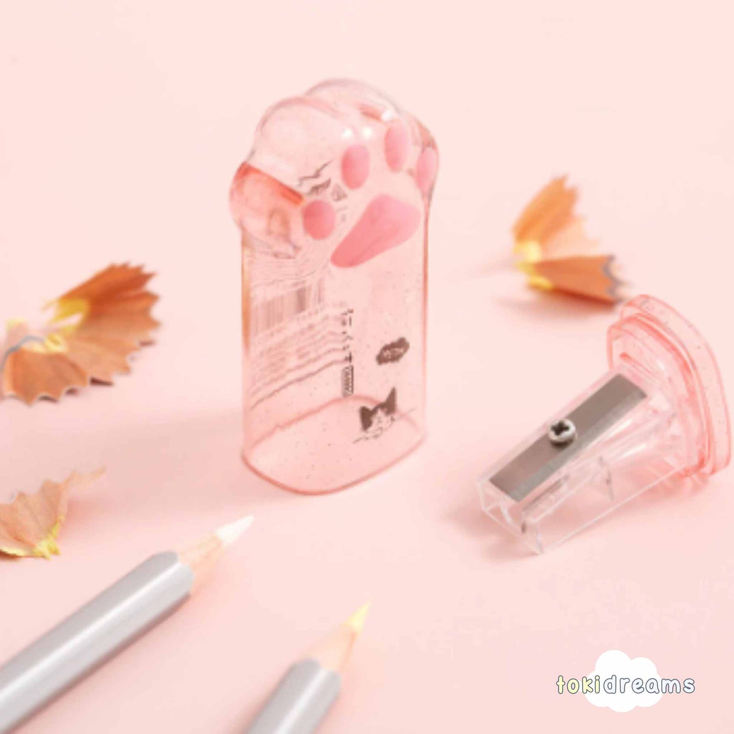 Two clear cat paw pencil sharpeners with pink accents, showing sharpener in use