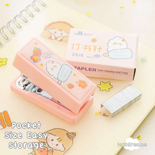 Pink mini stapler with matching refill kit featuring cartoon bear, placed on a notebook for scale and context
