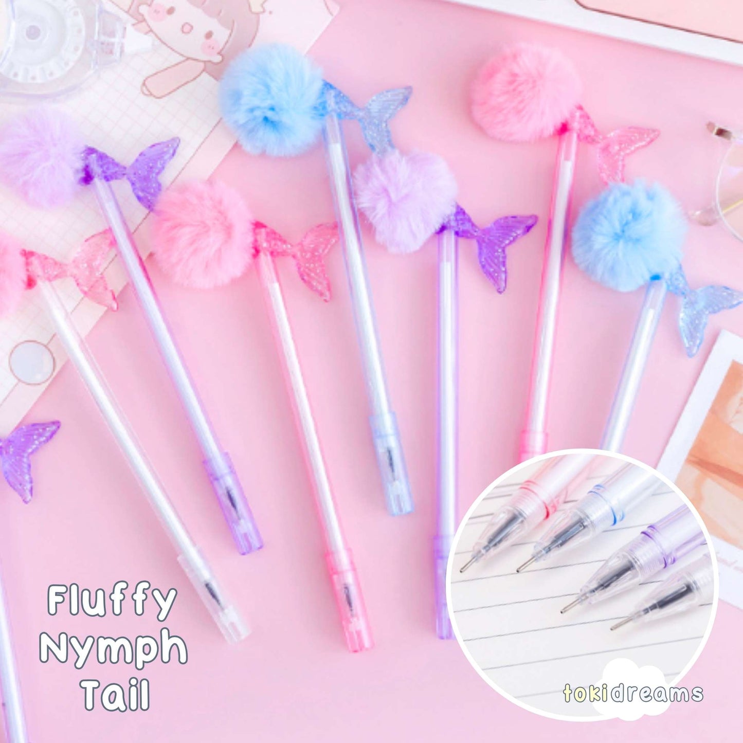 A collection of Fluffy Nymph Pens with pink, blue, and purple shimmering pom-pom tails, displayed on a desk with gel ink bottles and notes.