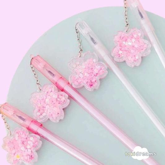Close up of flower swinging charm on ballpoint gel pen with pastel pink background.