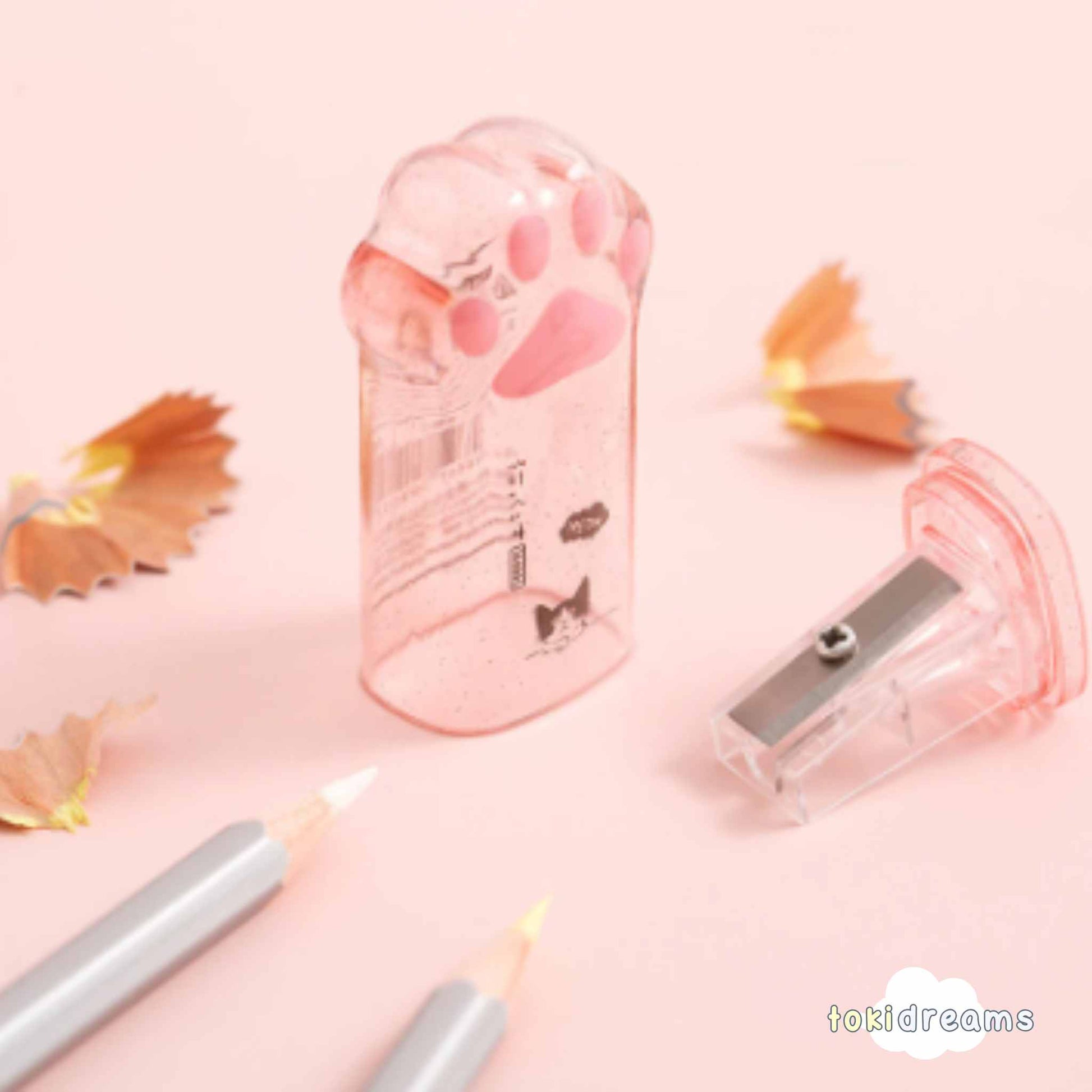 Two clear cat paw pencil sharpeners with pink accents, showing sharpener in use