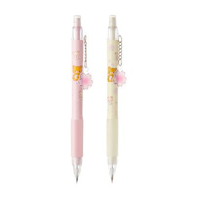 Two pens with cartoon character designs and flower charms on a white background