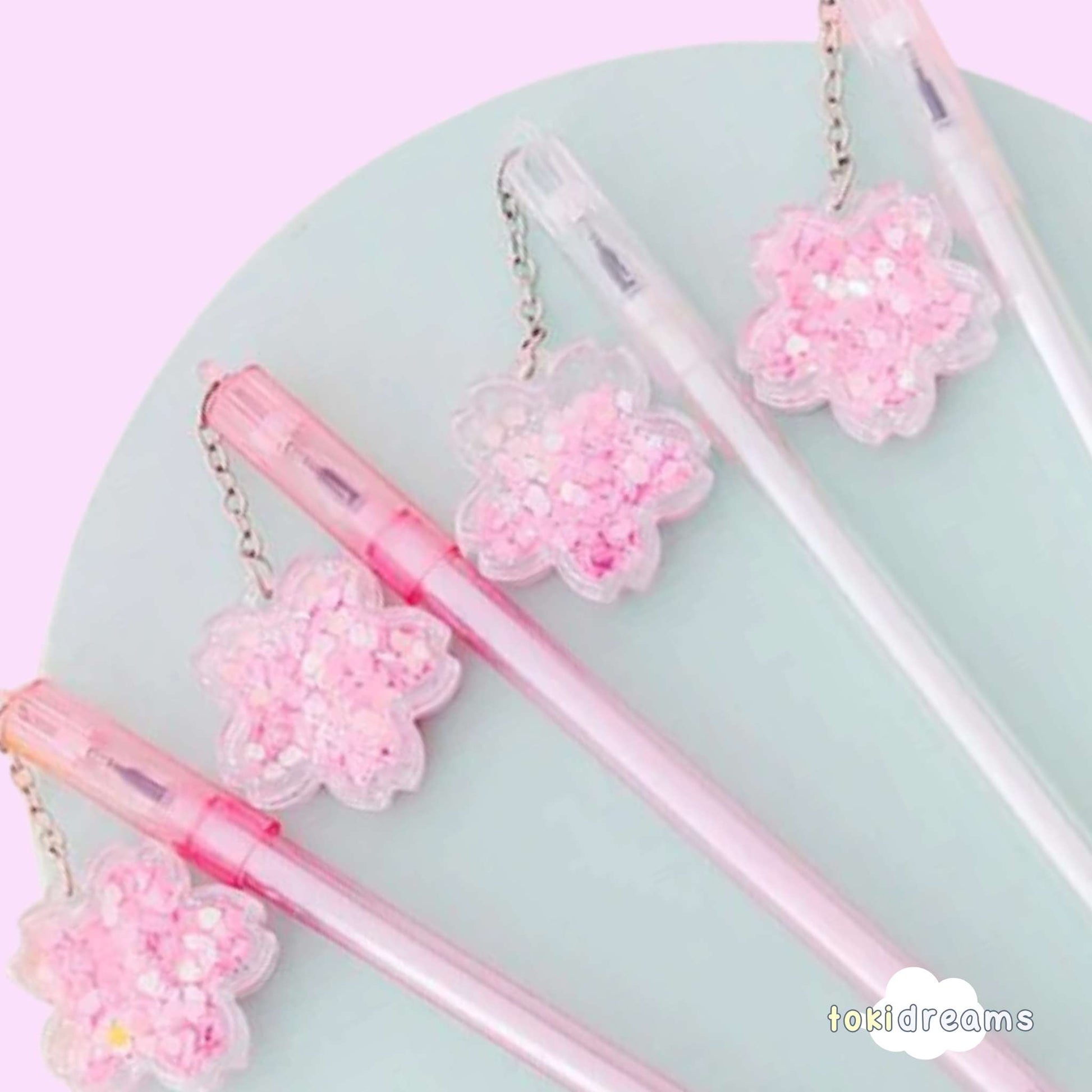 Close up of flower swinging charm on ballpoint gel pen with pastel pink background.